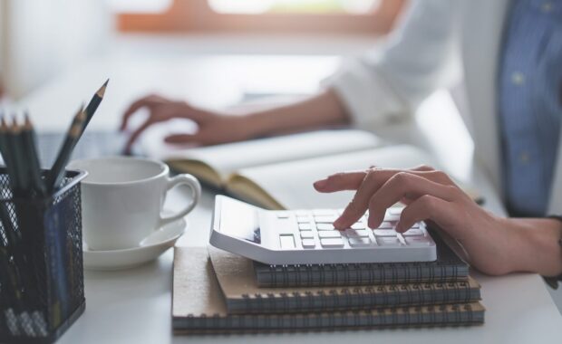 business woman or Accountant do math and analyze with calculator and paperwork on desk