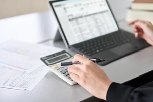 business women working on laptop and checking calculator