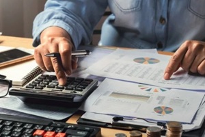 businesswoman working using calculator with money stack in office