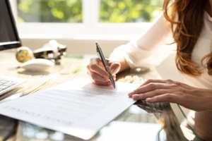 businesswoman's hand signing contract with pen