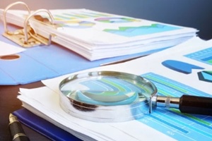 financial audit report and magnifying glass on a desk