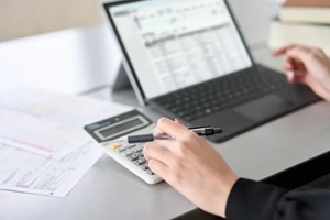 man using calculator while working on laptop