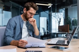 serious young man accountant, financier, analyst, auditor sits in the office at the table